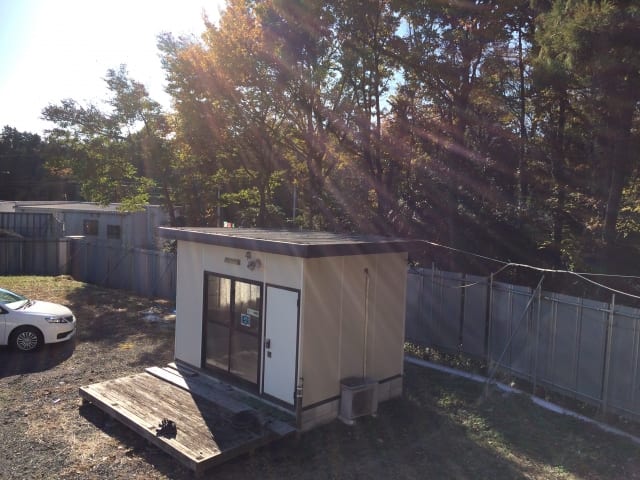 駐車場に立つプレハブ小屋