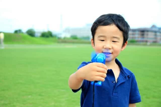 小型扇風機を持つ少年