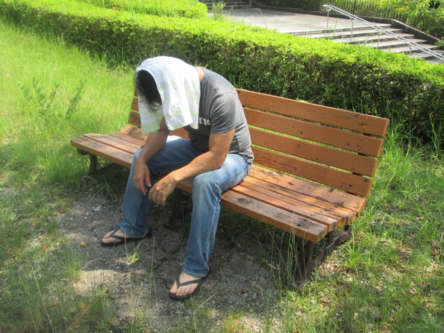 夏バテの男性がベンチで休む