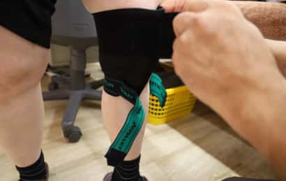 膝サポーターの上部ベルトを巻いているところ