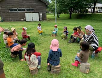 青空の下でおやつを食べる子どもたち