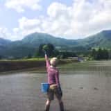 田んぼで手をあげる女性