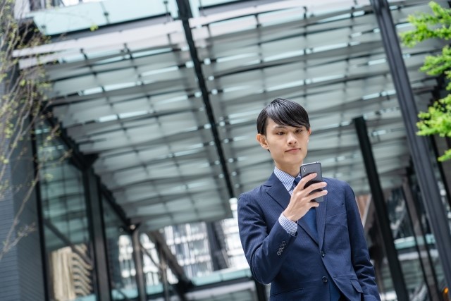 auのタフネススマホを持っているスーツ姿の男性